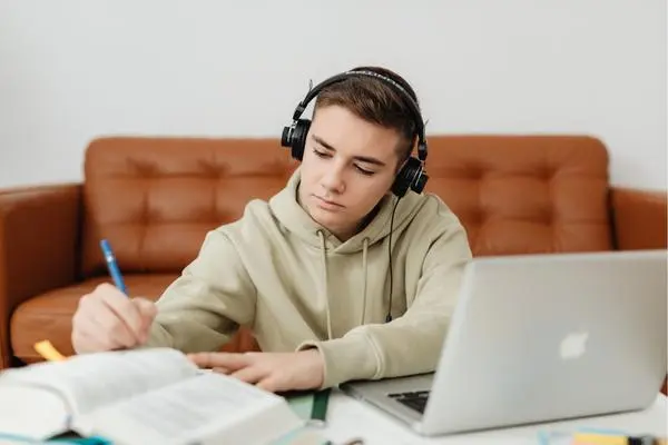 A student working on his assignment as he listens to music