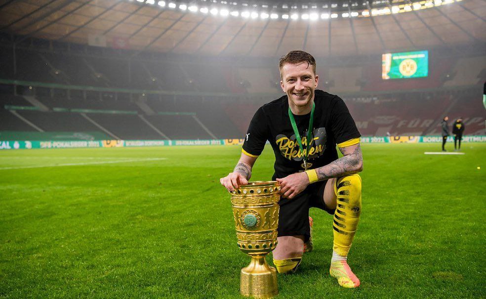 Marco Reus poses with the DFL Pokal following their victory in 2021. The German star has lifted a total of three DFL Pokal cups with Borussia Dortmund. He looks forward to winning more with the German side following his contract extension
